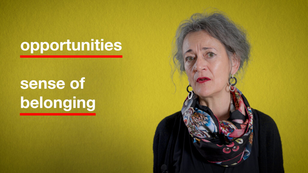 A woman standing in front of a yellow background with two sentences on her left ("opportunities" and "sense of belonging")